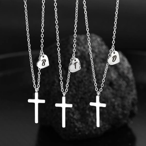 Three stainless steel cross necklaces with heart initial pendants on black volcanic stone