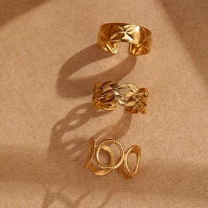 Detailed view of three stackable gold rings featuring quilted, chain, and layered designs