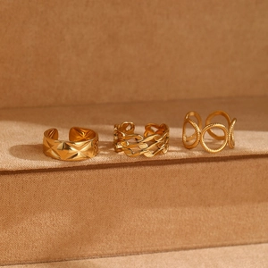 Close-up of three gold adjustable geometric rings on a velvet display stand