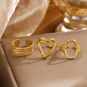 Detail of three gold hammered texture adjustable rings with heart and oval motifs