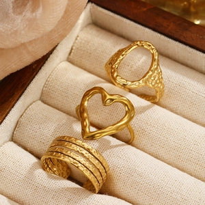 Detailed view of three gold-plated textured rings including heart and oval open designs