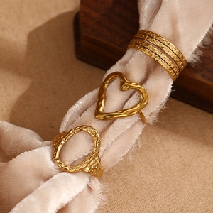 Detail of three vintage gold hammered rings featuring heart, oval, and multi-layer designs