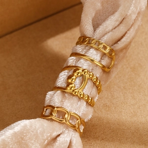 Detail of gold-plated woven chain ring set featuring luxury interlocking design on velvet