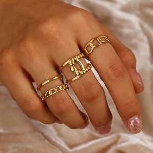Detail of four-piece gold woven chain ring set styled on model with velvet background