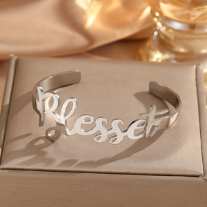 Macro shot of silver stainless steel cuff bracelet with Blessed cursive engraving