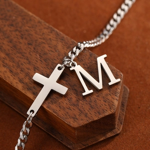 Macro shot of stainless steel anklet featuring a minimalist cross and M letter pendant