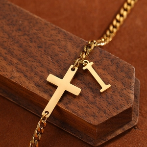 Macro view of gold stainless steel cross and capital letter I charms on a dense chain link