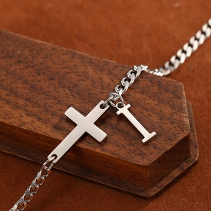 Detailed macro view of silver stainless steel cross and letter I charm anklet chain