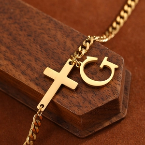 Close-up of golden stainless steel Cuban chain anklet with cross and letter G pendant