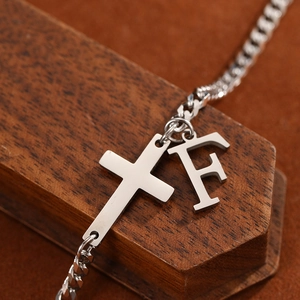 Macro shot of silver stainless steel cross and F letter pendant on a metal chain