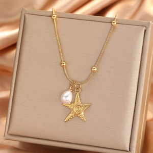 Collana con ciondolo a stella marina dorata e perla su portagioie in seta elegante