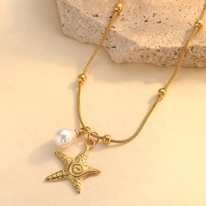 Collana con ciondolo a stella marina dorata e perla su sfondo in pietra naturale