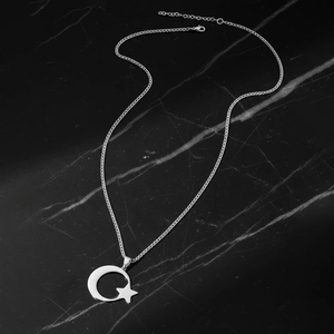 Collier en acier inoxydable avec pendentif lune et étoile sur fond en marbre noir élégant