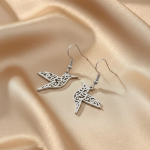 Boucles d'oreilles oiseaux en acier inoxydable sur fond de tissu en satin doré