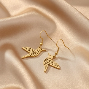 Gros plan détaillé des boucles d'oreilles colombe dorées avec motifs ajourés sur soie