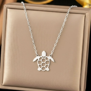 Elegant stainless steel necklace with hollow turtle pendant on champagne silk background