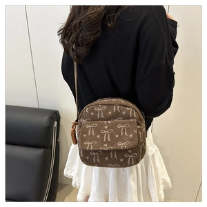 Sac bandoulière en velours côtelé marron avec motifs nœuds porté par un mannequin