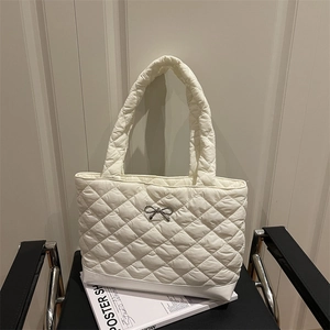 White quilted tote bag with silver bow detail and padded shoulder strap for daily use