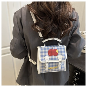 Detail view of mini blue gingham backpack with red apple design on a blazer background