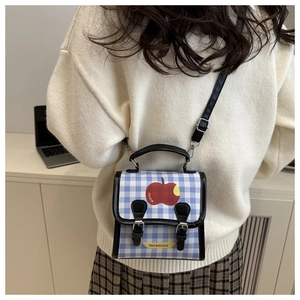 Detail of blue and white checkered mini crossbody bag with apple print and leather straps