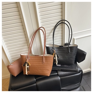 Close-up of woven tote bag set with beaded charm and matching zipper pouch in warm tones