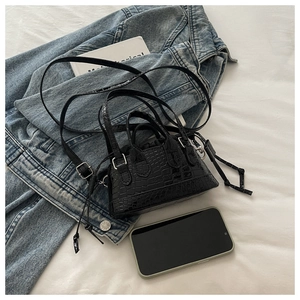 Detail of black croc-embossed mini Boston bag with silver hardware and crossbody strap