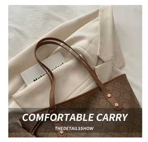 Detail of dark brown monogram tote bag with leather handles and gold rivet accents
