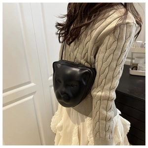 Detail of a unique black leather 3D mask-shaped crossbody bag with metal zipper