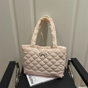 Quilted tote bag in pale pink with bow detail on a chair and fashion magazine