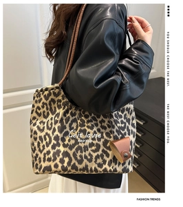 Detail of leopard print tote bag with brown straps and artistic text on soft suede
