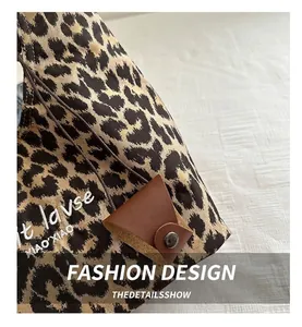 Detail of leopard print canvas tote with brown leather strap and buckle texture