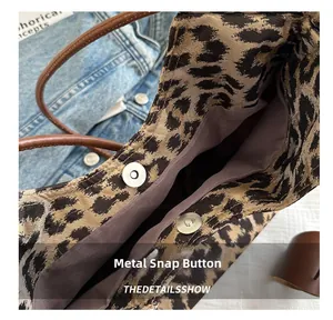 Detail of metal magnetic buckle closure on leopard print tote bag with brown leather strap