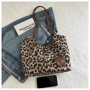 Detail of leopard print faux suede tote bag with brown straps and leather charm accessory