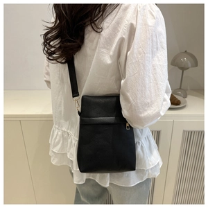 Detail of black lychee grain crossbody bag with gold hardware and zipper closure