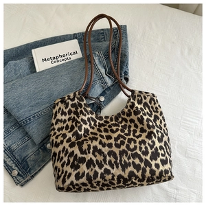 Close-up of leopard print tote bag with brown leather straps on a blue denim jacket