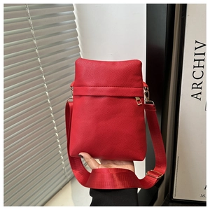 Detail of red pebbled leather crossbody bag with wide nylon strap and gold-tone zippers