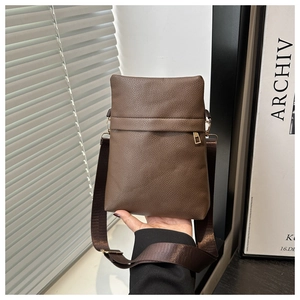 Detailed view of brown litchi pattern leather crossbody bag with wide shoulder strap