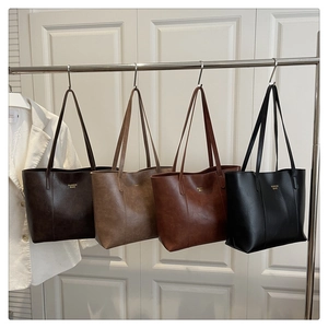Detailed view of four large PU leather tote bags hanging in coffee, brown, red, and black