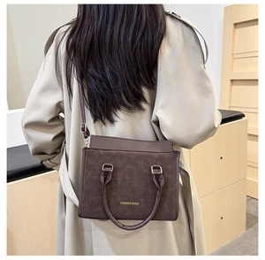 Mannequin portant un sac bandoulière vintage en cuir marron sur un trench-coat