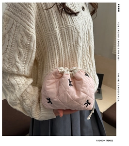 Detail of pink quilted drawstring makeup bag with black bow embroidery and white lining
