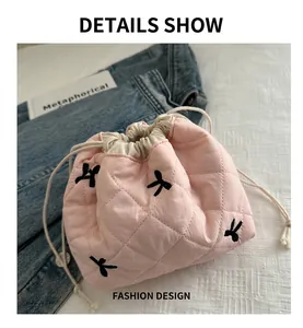 Dettaglio della trousse rosa trapuntata con coulisse e ricami a fiocco neri