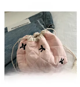 Detail of pink quilted drawstring makeup bag featuring black bow embroidery patterns