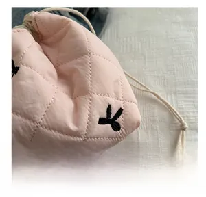 Detailed macro view of pink quilted fabric texture and black embroidered pattern on pouch