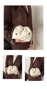 Macro detail of cream quilted drawstring pouch with embroidered black bow patterns