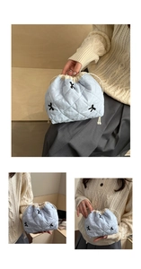 Detail of light blue quilted drawstring bucket bag with black bow embroidery and cord