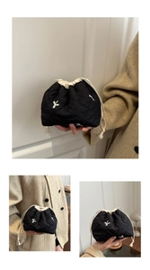 Detail of black quilted bucket bag with white embroidery and drawstring closure