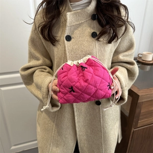 Rose pink quilted drawstring cosmetic bag with black embroidery held by a model