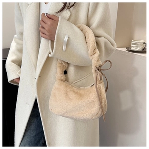 Detail of soft cream plush shoulder bag featuring a ruched handle and leather bow accent