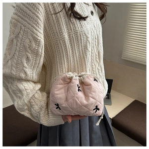 Detail of pink quilted drawstring makeup bag featuring black bow embroidery patterns