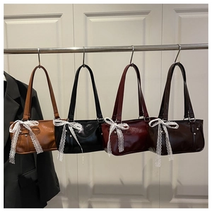 Detail of four colored underarm bags with lace bows in brown, black, red and coffee